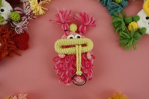 Macro detail of handmade crochet sausage mouth key case showing yarn texture and ring