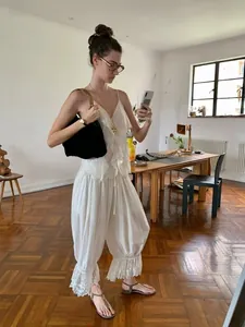 Λεπτομέρεια λευκού boho σετ με τοπ με βολάν και φαρδύ παντελόνι με δαντελένιο τελείωμα