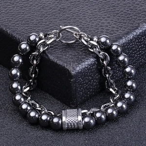 Detailed close-up of dark grey metal beaded bracelet with T-bar clasp on black box