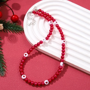 Festive Christmas pearl necklace with red beads and heart patterns on white arch display