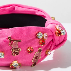 Dettaglio fascia annodata rosa con strass scintillanti e ciondoli con scritte Love