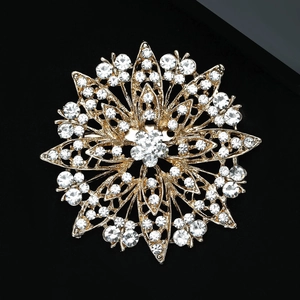 Macro shot of gold sunflower brooch with sparkling rhinestones on black background