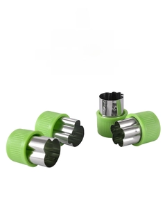 Macro detail of four stainless steel vegetable cutters with green protective handles