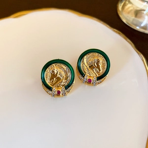Détail macro de boucles d'oreilles cheval vintage en or avec émail vert et cristaux