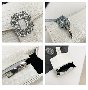 Detail view of white crocodile pattern leather bag with jewel buckle and silver chain