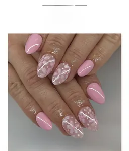 Détail de faux ongles amande roses avec motifs de fleurs blanches et pois