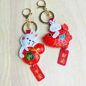 Close-up of rabbit leather keychains with lucky koi fish and gourd charms on wood