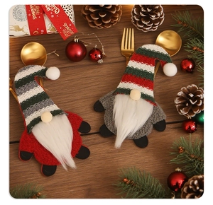 Detail of knitted Christmas gnome cutlery holders on a festive wooden table setting