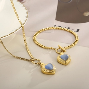 Détail du pendentif cœur doré avec opale bleue et parure de chaîne en acier à fermoir OT