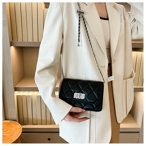 Close-up of quilted leather crossbody bag featuring metal chain strap and twist lock