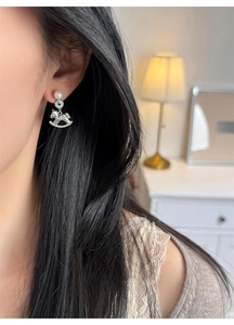 Detail shot of model wearing silver horse earrings with white pearl and pave crystals