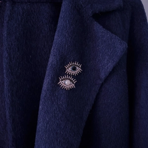 Vintage evil eye brooches with freshwater pearls and rhinestones on blue coat lapel