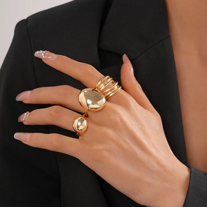 Close-up of golden oval pebble rings and multi-layer metallic rings on model hand