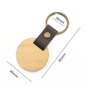 Detail view of round wood keychain with brown leather strap and dimensions labels