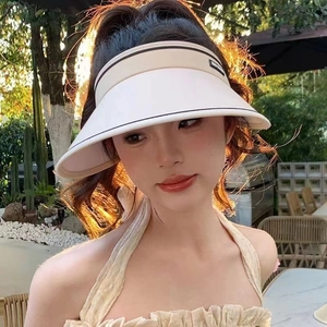Detail of off-white wide brim sun hat with black trim on a model in sunlight