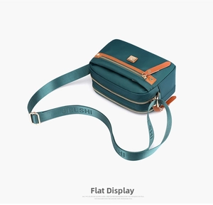 Detail view of water-resistant dark green nylon crossbody bag with multi-zipper layers