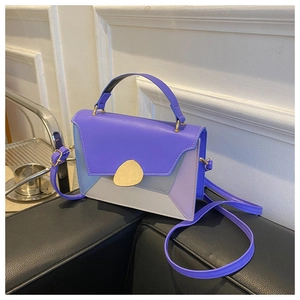 Chic color-block crossbody bag with metal buckle and top handle on black sofa