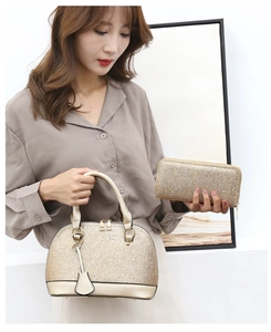 Detailed view of the gold sequined handbag and long wallet set held by a model