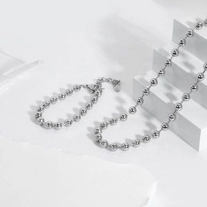 Detailaufnahme von 6mm Silber-Edelstahlperlenkette und Armband auf weißem Steinpodest