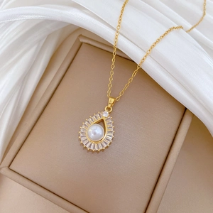 Close-up of golden teardrop necklace with pearl inlay and clear crystals on silk fabric