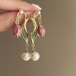 Macro detail of tulip flower earrings with pink enamel and round pearl drops