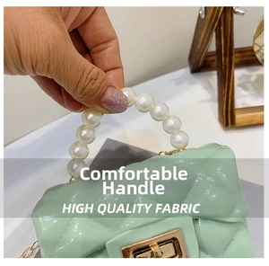 Detail of mint green quilted jelly bag featuring a pearl handle and gold twist lock
