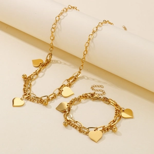 Golden double-layer chain jewelry set with heart and bead pendants on beige display