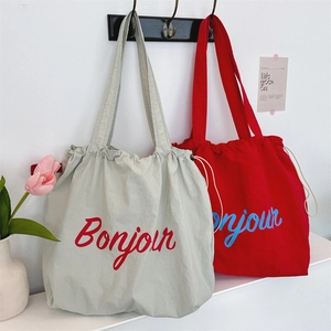 Detail of canvas tote bag with drawstring closure and Bonjour lettering in two colors