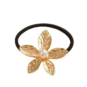 Minimalist gold metal flower hair tie with pearl center and textured petals on black elastic
