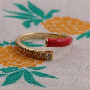 Detail of adjustable gold ring featuring red enamel and pavé white cubic zirconia