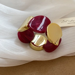 Détail du bracelet élastique large avec modules en résine rouge foncé et métal doré