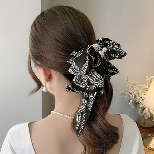 Elegant black and white houndstooth bow hair clip with pearl accent on female model