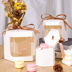 Close-up of white hexagonal gift boxes with clear window and brown satin ribbon accents