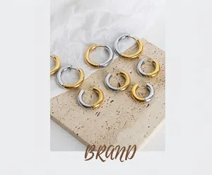 Macro shot of minimalist gold and silver dual-tone hoop earrings on textured stone