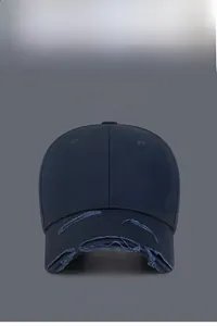 Detail view of navy blue baseball cap showing distressed torn brim and canvas texture