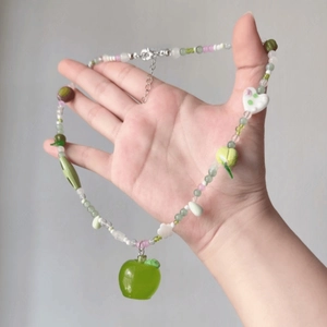 Detail view of handmade resin apple pendant necklace with colorful beads and floral accents