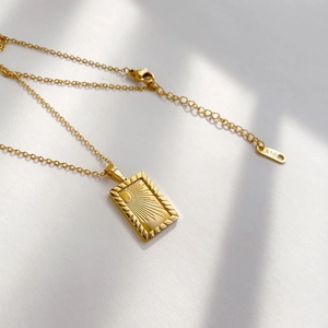 Macro detail of sunburst textured rectangle pendant with K18 gold hallmark stamp
