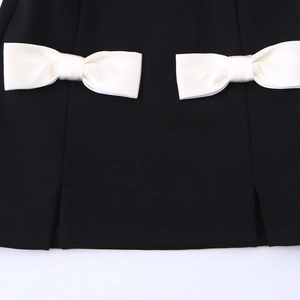 Chic black sleeveless dress featuring white satin bows and a stylish side slit detail