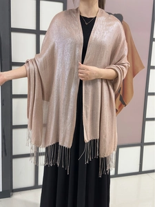 Detailed view of pink sparkling scarf with fringe tassels worn over woman's shoulders