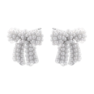 Detailed close-up of bow knot stud earrings featuring dense white faux pearl inlay on silver metal