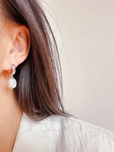 Primo piano di orecchini ovali minimalisti in argento con opale indossati da una modella