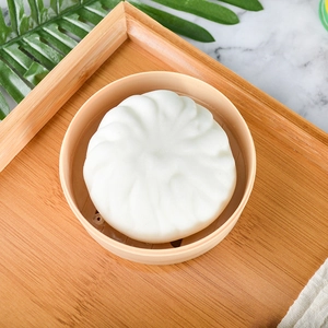 Squeeze bun toy in small plastic steamer basket on a wooden tray table setting
