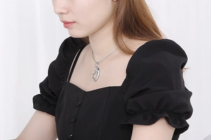 Close-up of heart-shaped hollow pendant necklace worn by a model in black outfit