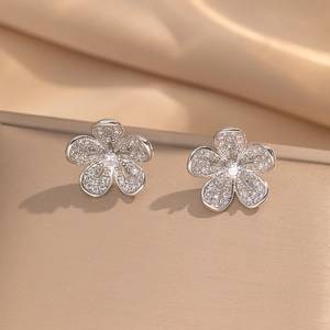 Elegant five-petal flower stud earrings with sparkling white zircons on silk background