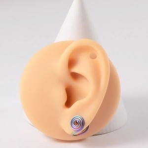 Macro shot of colorful iridescent spiral ear cuffs on skin-textured ear model