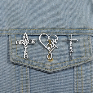 Detail of silver lettered brooches on denim featuring Amazing Grace and Faith text