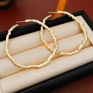 Détail de créoles dorées à surface texturée irrégulière dans un écrin à bijoux