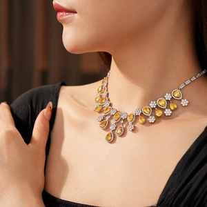 Detail of silver necklace featuring yellow teardrop stones and zircon floral pendant