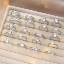 Detailed top view of various silver zircon rings arranged in a beige velvet jewelry box