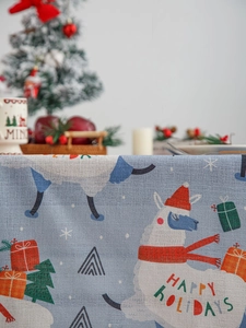 Detail of blue Christmas tablecloth with alpaca prints and Happy Holidays text